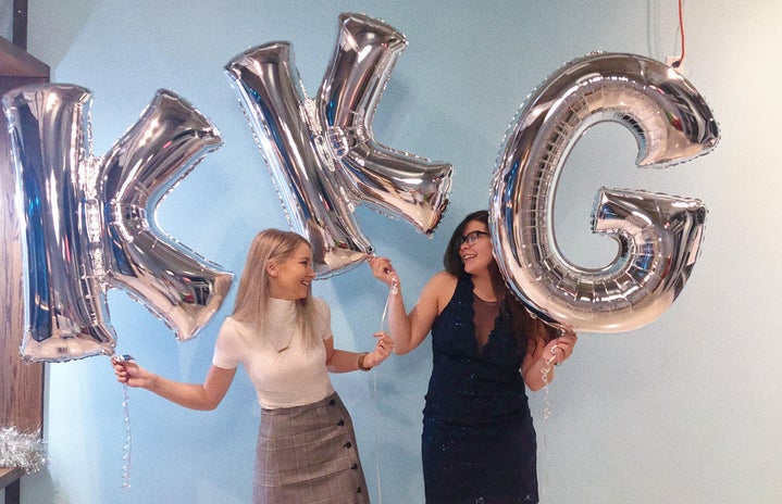 two sorority sisters holding silver KKG balloons