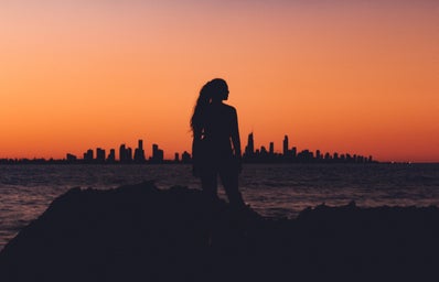 Woman standing in the sunset in front of a city