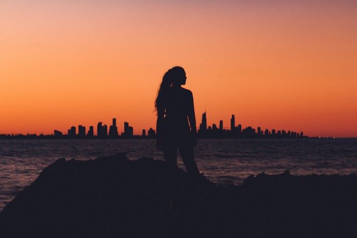 Woman standing in the sunset in front of a city