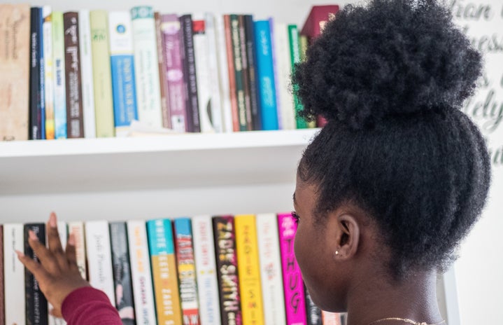 young black girl looking at bookshelf