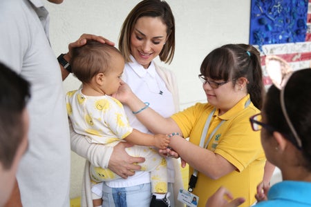 Nikki Sapp-Spoelstra holding her son, next to a student in a yellow polo