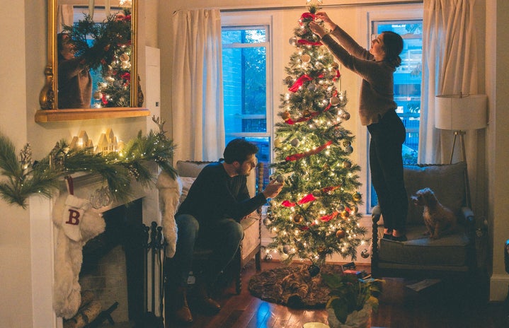 a couple decorating a Christmas tree
