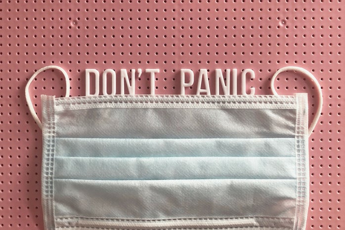 mask on a pink letterboard with the words "don't panic" written