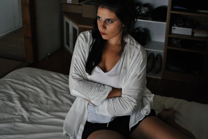 Woman sitting on bed with angry expression