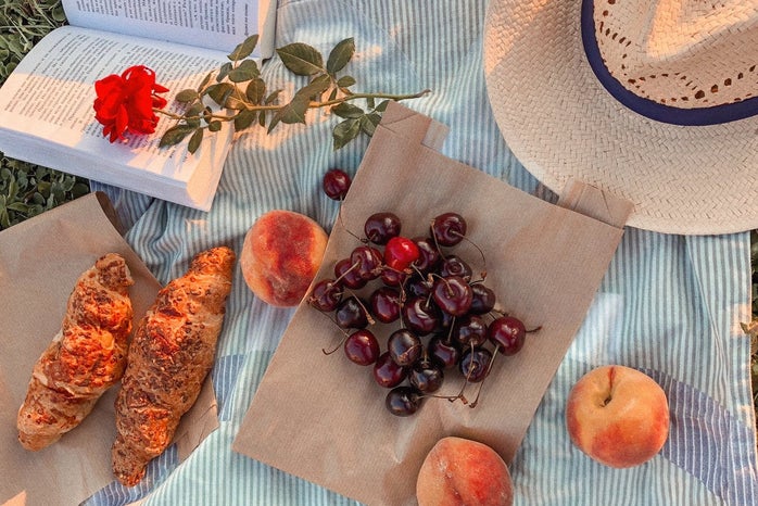 a picnic blanket set with cherries and pastries