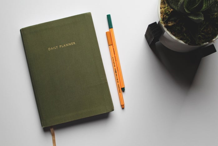 green book beside orange and white pen photo