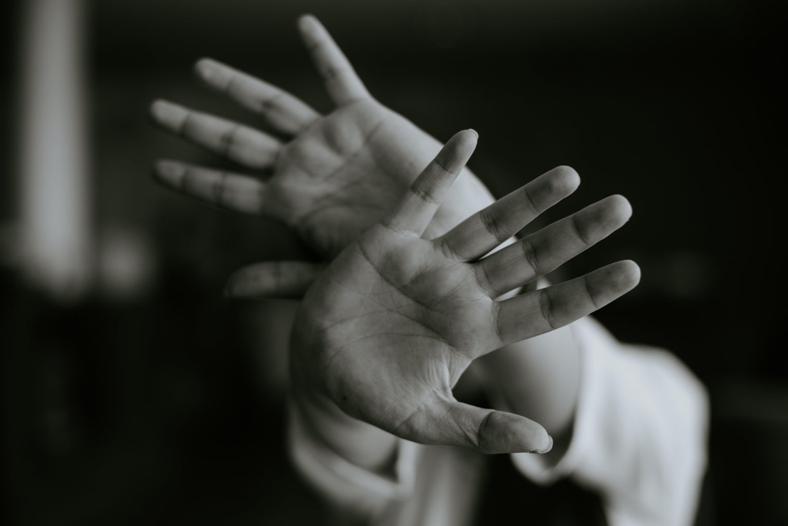 Person stretching out their hands to the camera in a \'stay away\' gesture