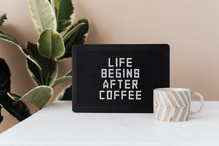 Message board with funny motto and cup of coffee