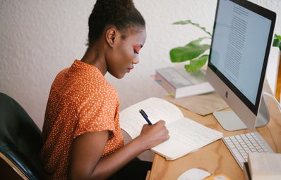Black girl at computer desk writing in journal write natural work corporate african
