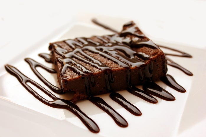 Brownie on white plate with chocolate drizzle