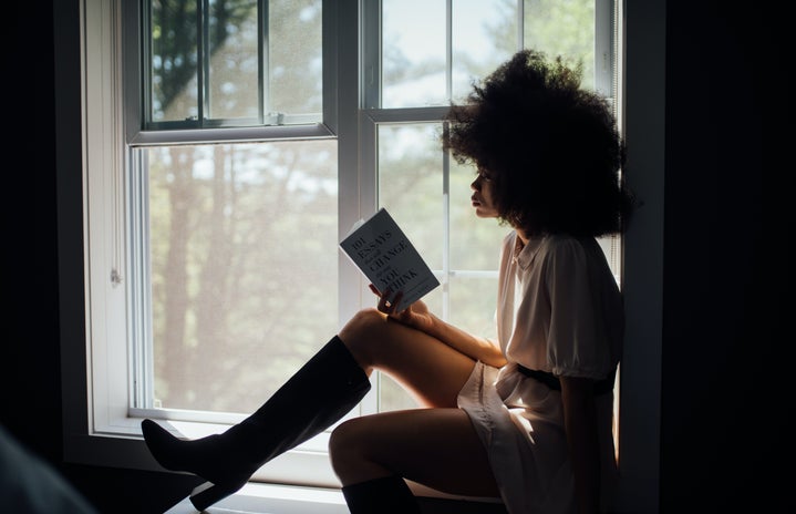 Woman reading a book in a windowsill.