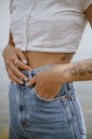 person with tattoos poses with their hand in their pocket