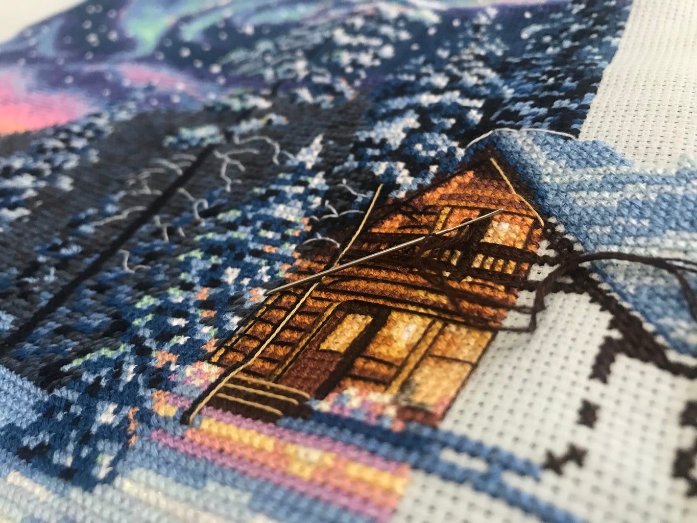 Cross stitch of cabin and northern lights