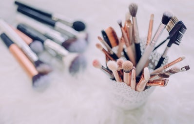 cup of makeup brushes with more brushes laying beside it on the table