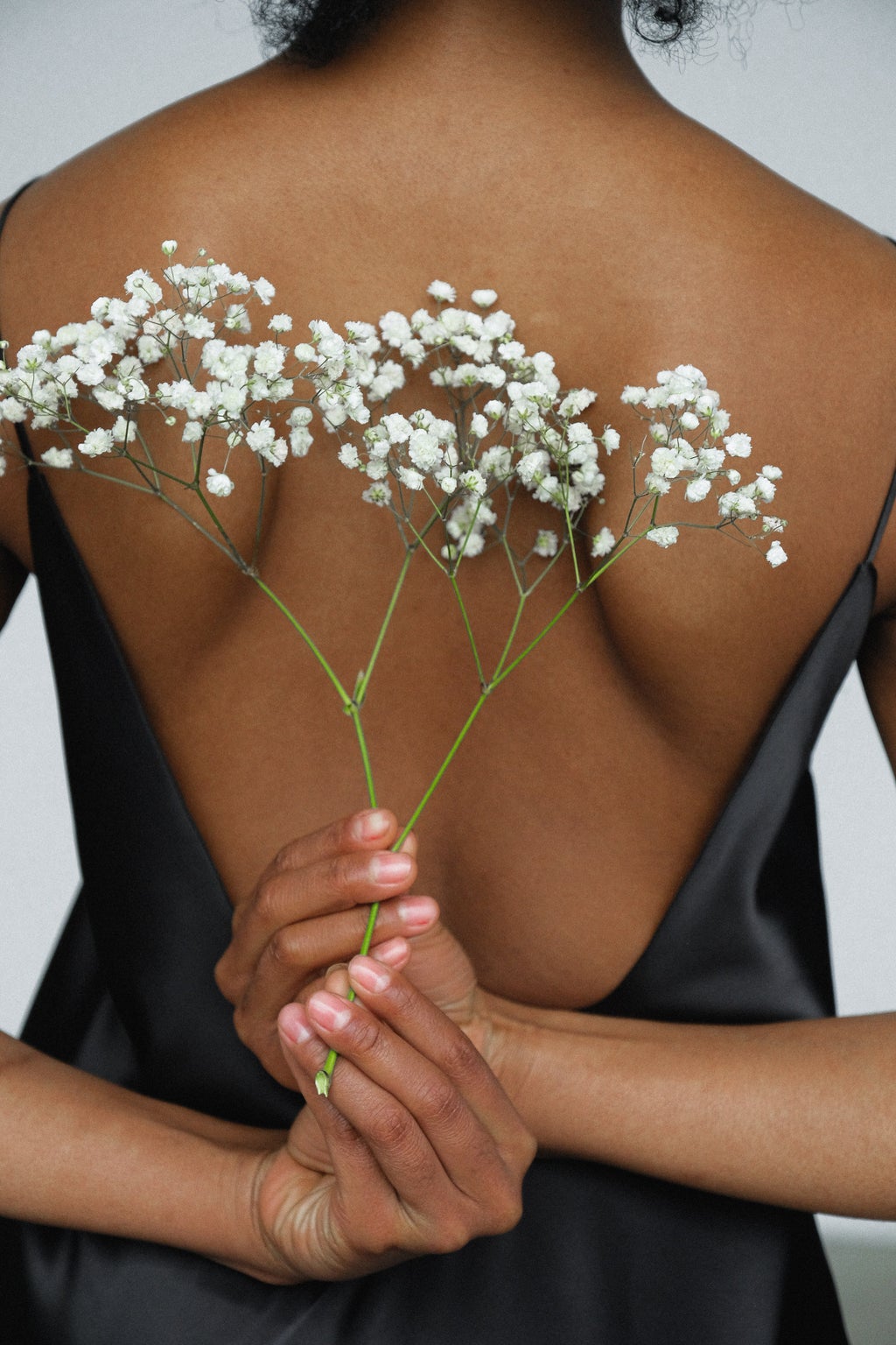 Black woman holding flowers behind back