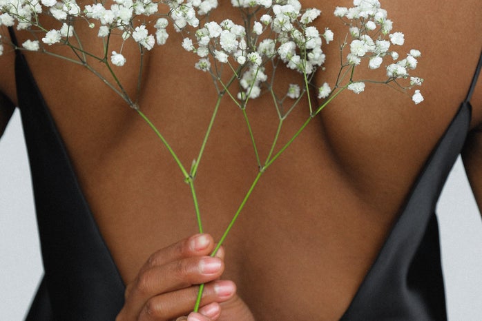 Black woman holding flowers behind back