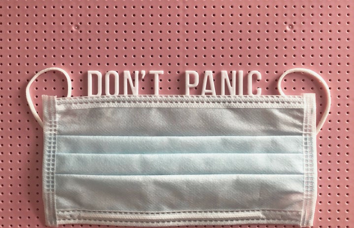 reuseable surgical mask with phrase \"don\'t panic\" on a pink letter board