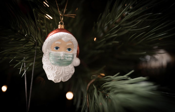 Santa ornament wearing a mask and hanging on a tree
