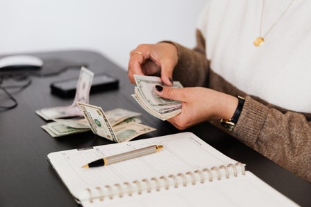 payroll clerk counting money while sitting at table