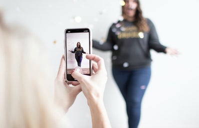 woman filming vertical video of woman throwing confetti