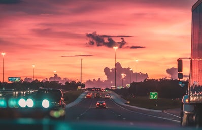 view from a windshield of the highway with a pink sky