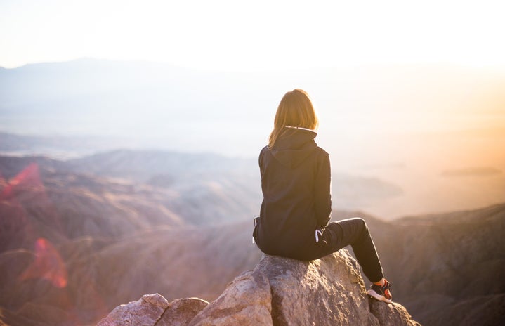 Woman sitting on top of mountain at sunrise