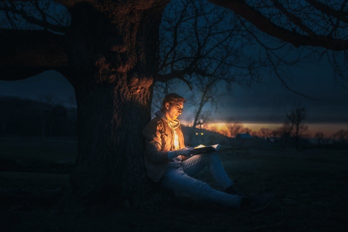 man leaning against tree and reading