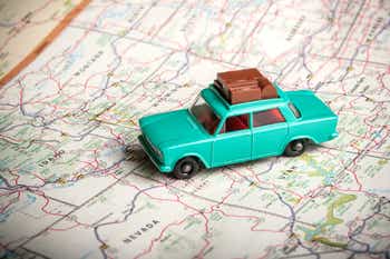 Vintage toy car with luggage on the roof with a road map of the U.S.