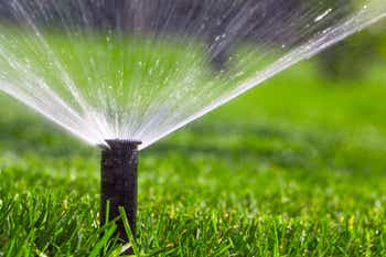 Close-up of an automatic sprinkler system watering the lawn on a background of green grass