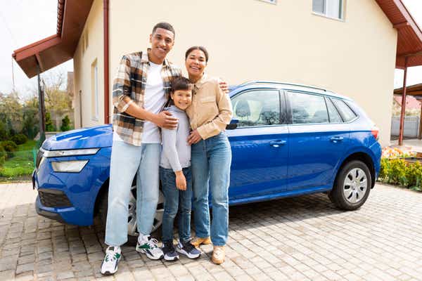 Happy family with their son arrived by car to their new home, posing and embracing