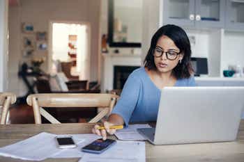 Young woman using a laptop and calculator while working from home