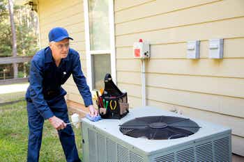 Technician services an outdoor AC unit at house