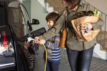 Mother and son charging their electric car at home