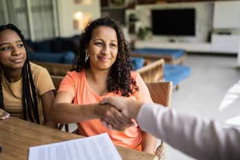 Helpful insurance agent shakes hand of insured after reviewing claim paperwork
