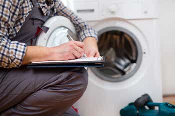 Repairman is repairing a washing machine.