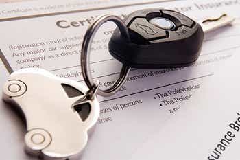 Car keys over sitting on top of car insurance papers