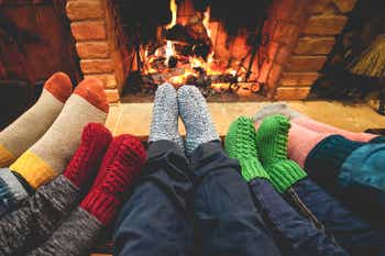 Happy family wearing warm socks in front of fireplace