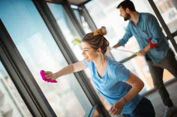 Closeup side view of a young couple cleaning windows before moving out of their apartment.