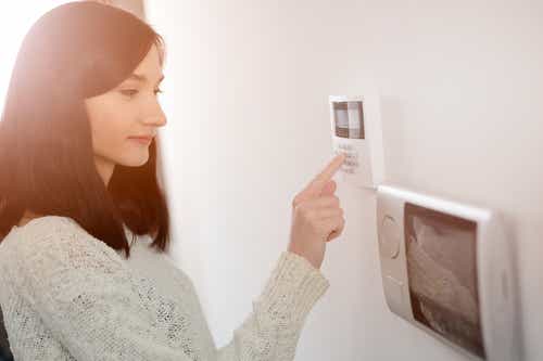 Young brunette woman entering code on keypad of home security alarm. Video intercom next to alarm keypad