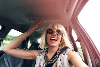 Young blonde woman in a car smiling and driving excitedly