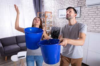 Couple in home catching ceiling water leak in buckets