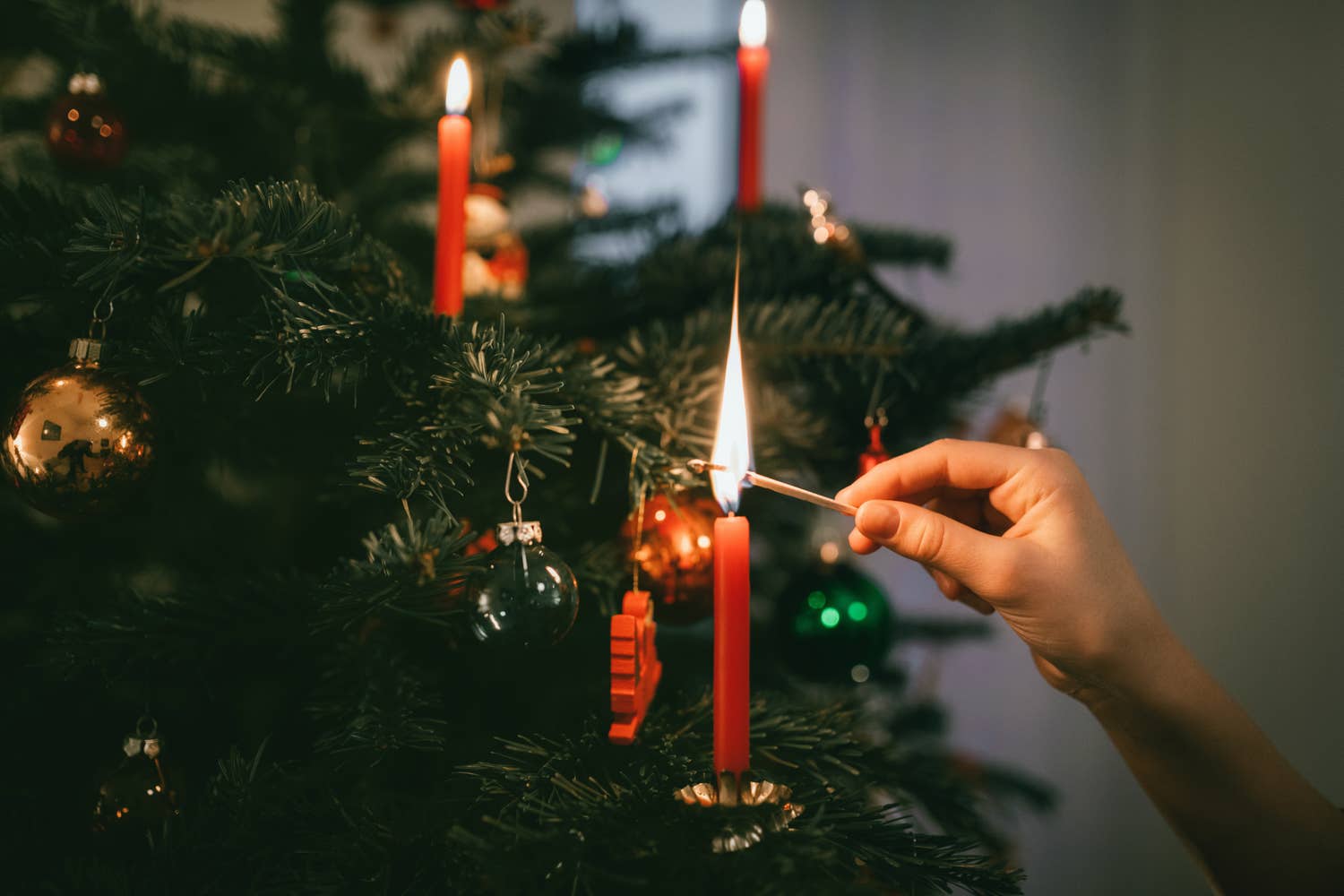 Hand lighting candle on a christmas tree