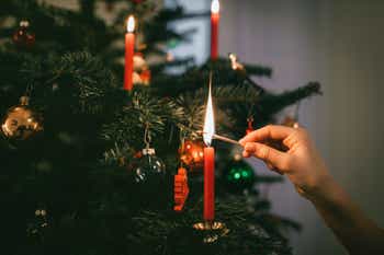 Hand lighting candle on a christmas tree