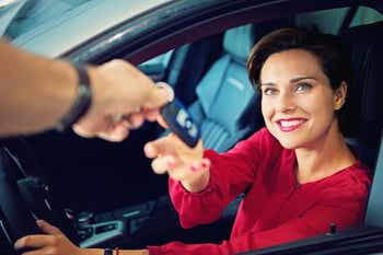 Dealer handing car keys to happy businesswoman