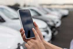 Close-up on a woman using a mobile app on her smartphone at a car dealership