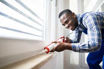 Homeowner applying a caulk sealant to window seal