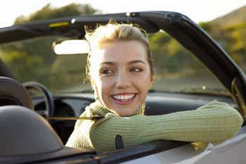 Woman smiling in passenger seat of convertible car