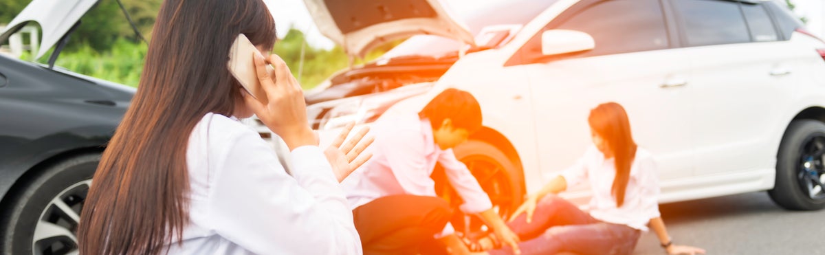 Young woman with smartphone by the damaged car after a car accident, making a phone call and for insurance agent to quick attention