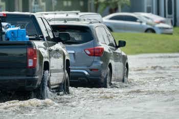 Hurricane rainfall flooded Florida road with evacuating cars and surrounded with water houses in suburban residential area