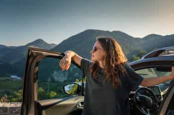 Young beautiful woman traveling by car in the mountains, summer vacation and adventure